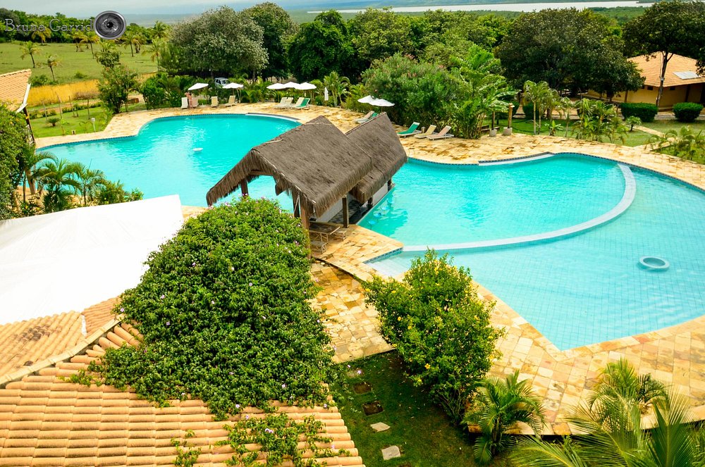 Vista aérea das piscinas em curva cercadas de palmeiras e jardim tropical
